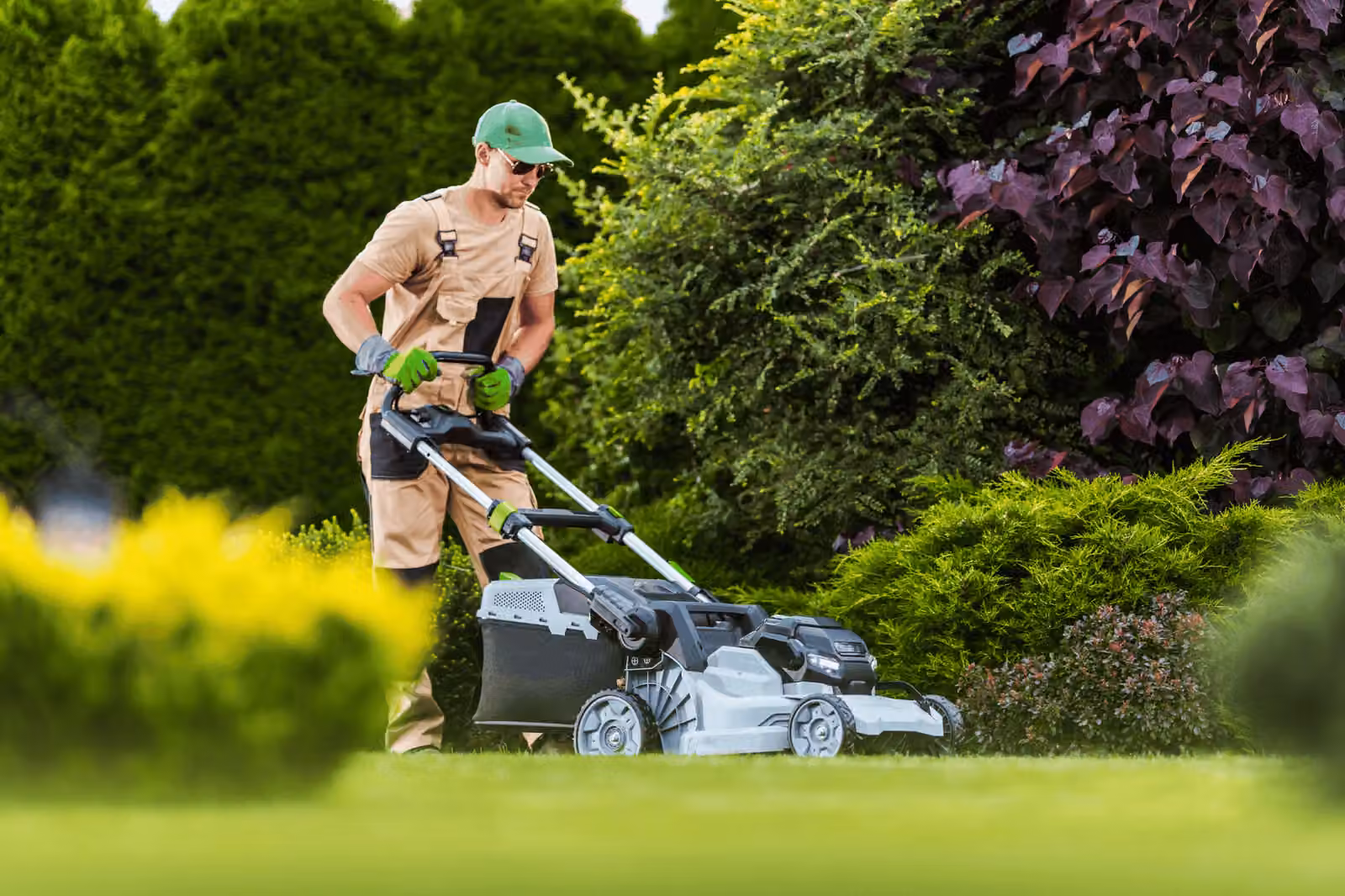 Gärtner mäht Rasen in einem gepflegten Garten